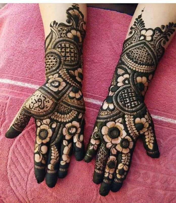 250+ Best Mehndi Designs for Hand Picture and Videos 85 black mehndi applied on both hand frot side palm and place hand on red cloth