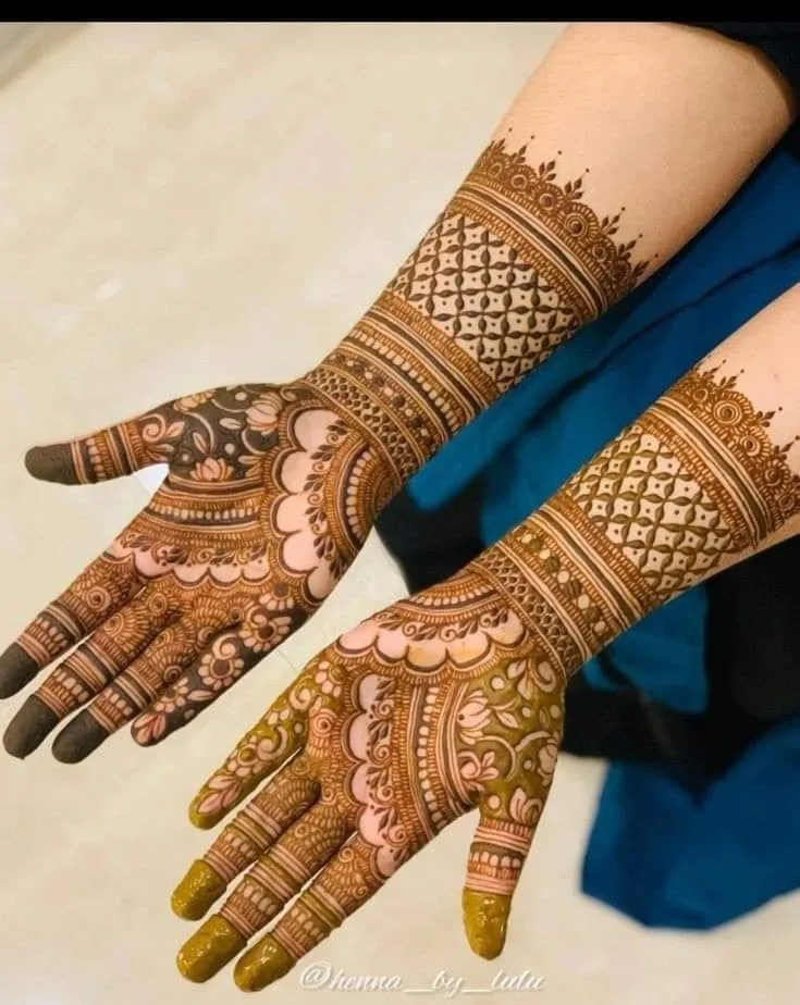 250+ Best Mehndi Designs for Hand Picture and Videos 75 female sitting and showing front hand plam mehndi design wearing blue shirt