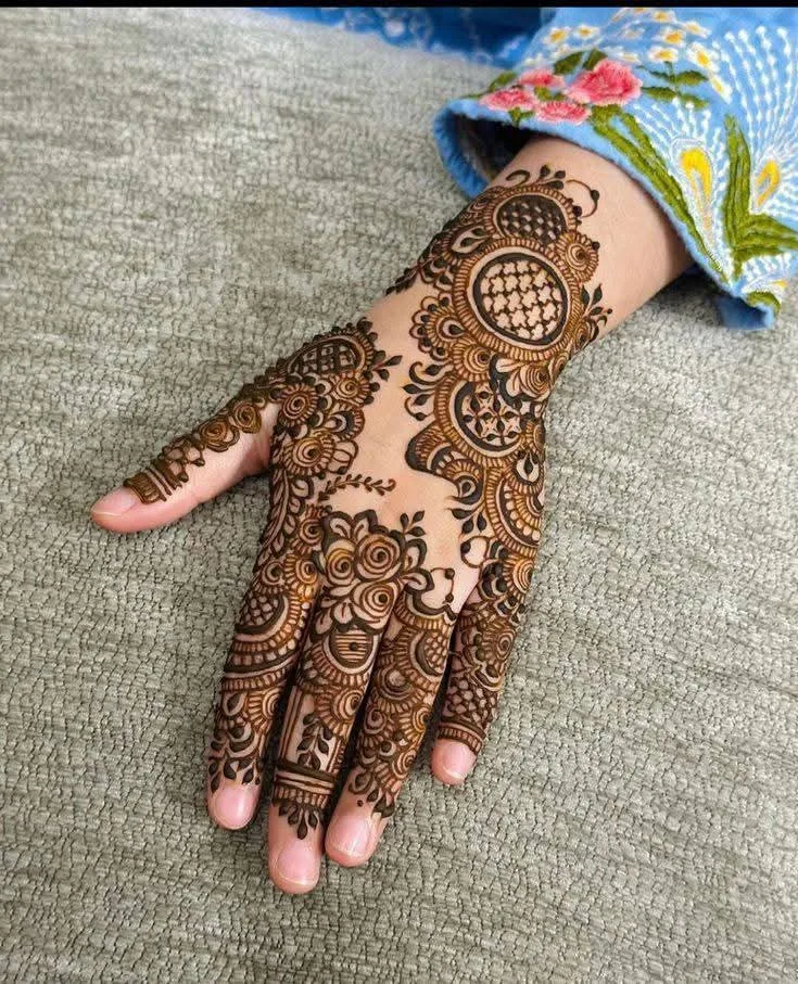 250+ Best Mehndi Designs for Hand Picture and Videos 21 placing hand on surface wearing flower shirt and mehndi on back hand side