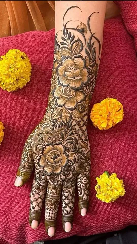 50 Best Backhand Mehndi Design Pictures and Videos 58 showing mehndi design on back hand side with yellow flower and red base